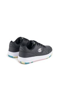 Sneakers in pelle nera con suola bianca, caratterizzati da un fondo testurizzato multicolore e un logo metallico sul lato.