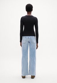 Top nero a maniche lunghe abbinato a jeans a gamba larga azzurri. L'outfit presenta un top slim fit e un design a gamba dritta con vita alta.