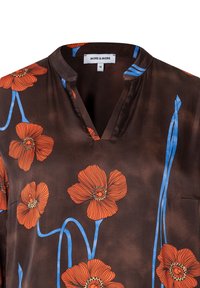 Bruine blouse met levendige oranje bloemenprint en blauwe stelen. Opvallend V-hals ontwerp met korte mouwen en een borstzakdetail.