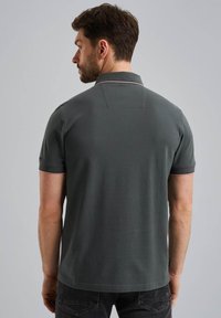 Polo shirt gris foncé avec un col à deux boutons, des manches courtes et des accents rayés contrastés sur le col et les bords des manches.