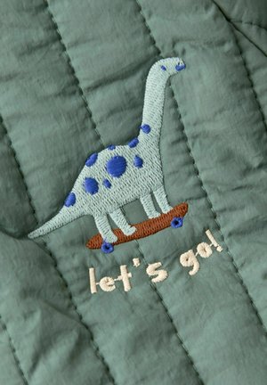 Gepatchter Stoff in gedämpftem Grün mit einem gestickten Dinosaurier auf einem Skateboard, versehen mit blauen Punkten und dem Text "Lass uns gehen!" in Beige.