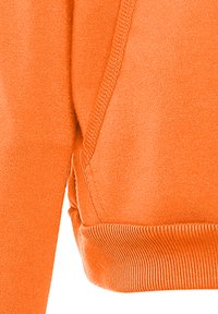 Felpa arancione con una texture morbida, polsini a costine e cuciture laterali con un leggero dettaglio arricciato.