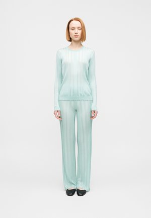 Haut en maille côtelée de couleur menthe claire et pantalon large assorti, tous deux à manches longues et coupe décontractée. Chaussures noires à enfiler incluses.