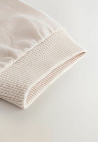 Light pink ribbed cuff, soft texture, folded edge, neatly stitched, suitable for sweatshirts or casual wear.