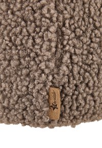 Brown curly textured wool fabric with a small tan suede tag featuring a stitched star and cursive brand name.