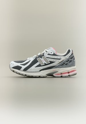 Zapatilla de running New Balance 1906R en gris y blanco con detalles en rosa y parte superior de malla, mostrada de perfil sobre un fondo neutro.