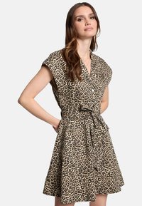 Robe imprimé léopard en brun clair et noir, avec un design noué, des manches courtes et une ceinture à nouer à la taille. Tissu au toucher doux.