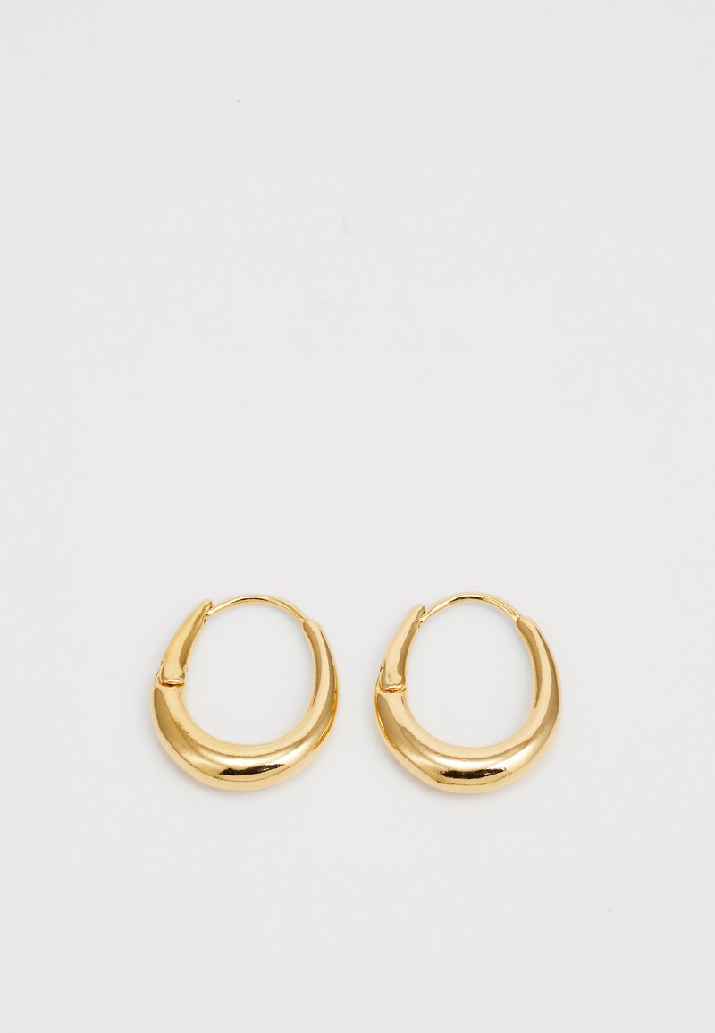 Guldtonade hoopörhängen med en slät, rundad design och små indragningar. De har ett säkert gångjärnslås för enkel användning.