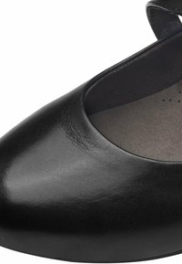 Chaussure Mary Jane en cuir noir avec bout arrondi, semelle intérieure grise rembourrée et une bride de cheville visible en haut à droite.
