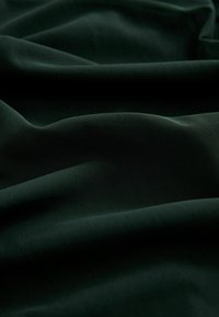 Mörkgrön, texturerad tyg med en mjuk hängning, som har en subtil lyster och en mjuk yta, idealisk för kläder eller möbelklädsel.