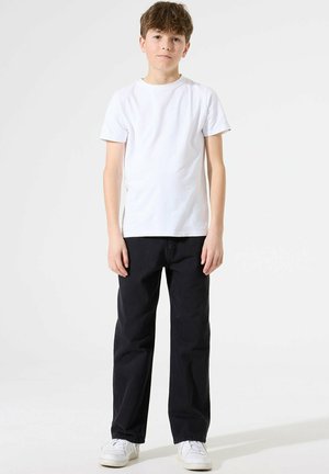 T-shirt blanche à manches courtes associé à un jean droit bleu foncé et à des baskets blanches. Design simple, matériau en coton, sans motifs visibles.