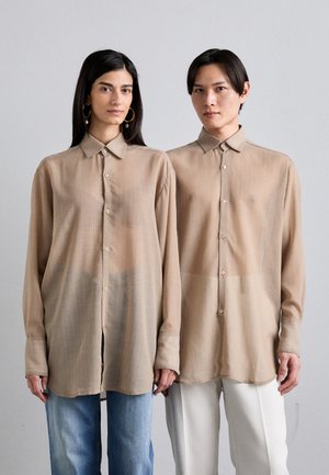 Translucent beige button-up shirts with a textured stripe pattern, featuring long sleeves and rounded hems, worn over blue and white bottoms.
