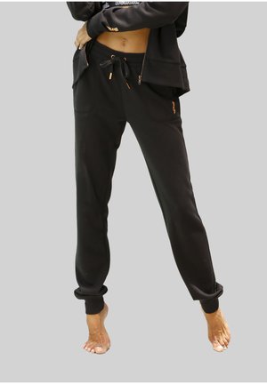 Black jogger pants with a drawstring waist, two front pockets, and ribbed cuffs. Features subtle logo accents in orange. Smooth texture.