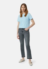 Lichtblauw katoenen T-shirt, relaxte pasvorm, gecombineerd met grijzige rechte jeans en roomkleurige flats met een gaasdetail en accenten.