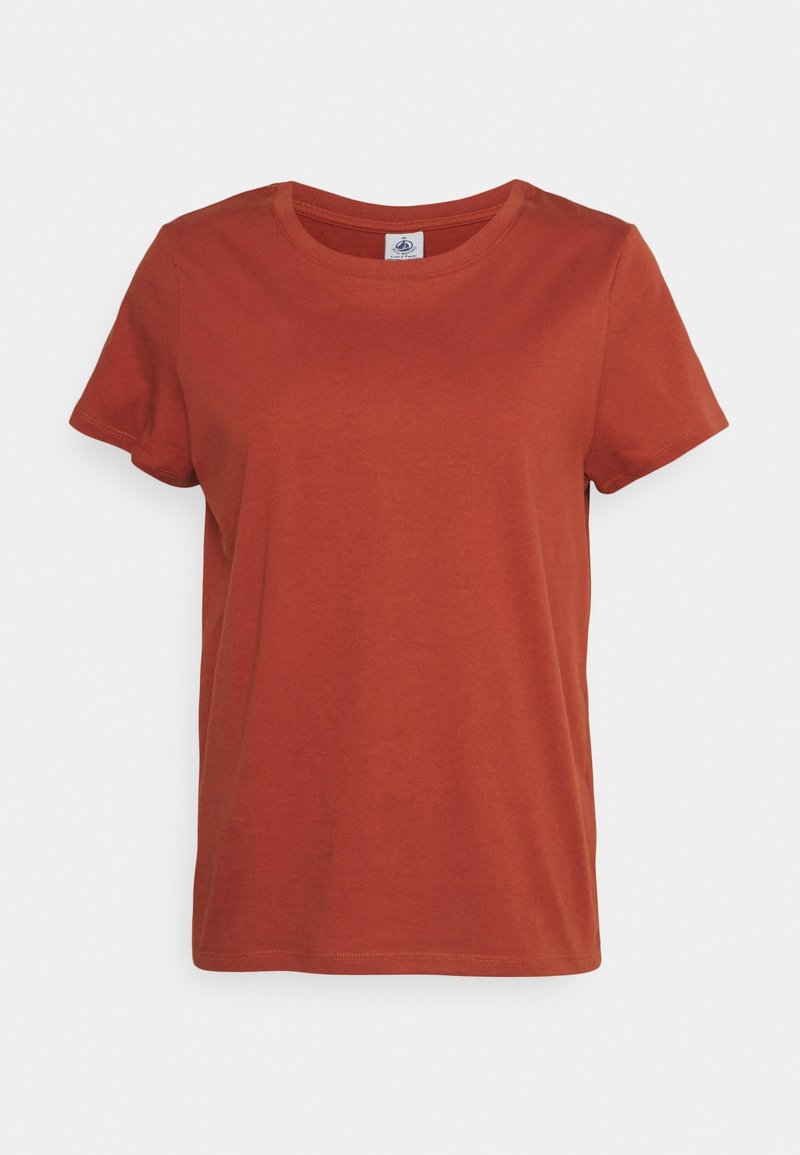 T-shirt uni à manches courtes et col rond de couleur orange rouille, présenté sur un fond blanc uni.