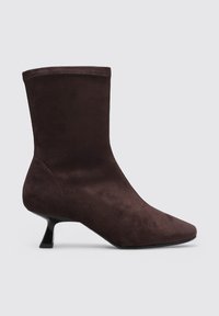 Bottine en daim marron avec un bout effilé, une forme ajustée et un petit talon conique. Texture lisse sans quincaillerie ou embellissements visibles.