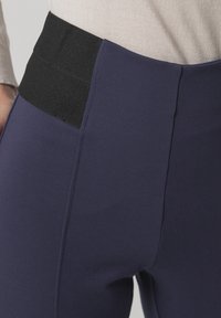 Rekbare marineblauwe legging met een zwarte elastische tailleband. Kenmerkt zich door een gladde textuur en zijnaaddetails voor een aansluitende look.