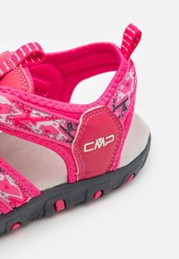 Rosa sandaler med ett mönstrat tygövre, justerbara remmar, en texturerad fotbädd och en slitstark svart gummisula med rosa accenter.