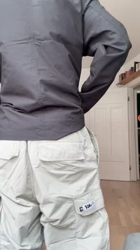 Mörkgrå långärmad topp med avslappnad passform och sydda sömmar, tillsammans med ljusgrå cargo-byxor med flera fickor.