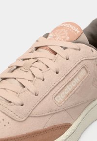 Ροζ σουέτ αθλητικά παπούτσια με επίπεδα κορδόνια, λογότυπο Reebok, επενδυμένο κολάρο και καφέ δερμάτινη λεπτομέρεια στη σόλα. Υφασμάτινη επιφάνεια και μαλακά υλικά.