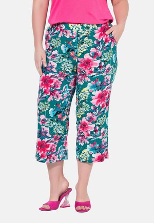 Blomsterprintet bukser i teal med pink, hvide og grønne blomster, med elastisk talje og sidelommer. Sæt med pink hæle.
