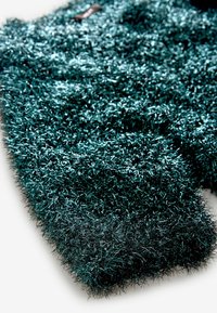 Tessuto verde acqua sfocato con fibre sottili lucide che creano una superficie texture. Presenta un aspetto morbido e peloso con lievi variazioni nella profondità del colore.