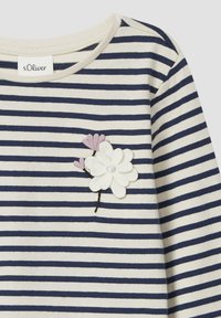 Gestreept shirt van crème en marineblauwe stof met een textuurrijke florale borduursel van een witte bloem en roze accenten aan de linkerkant.