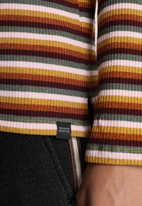 Haut côtelé présentant des rayures horizontales en bordeaux, vert, or et rose. Comprend une étiquette Maison Scotch à l'ourlet.