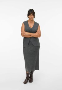 Gray wool blend sleeveless vest with two buttons, paired with a matching long skirt. Brown knee-high boots complete the outfit.