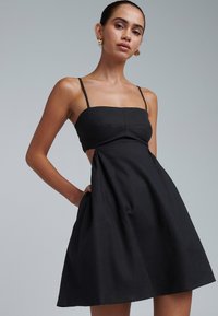 Must kleit õhukeste rihmadega, keha jälgiv ülaosa, külgedel lõiked ja lehvikukujuline seelik. Sile tekstuur, minimalistlik disain, põlvekõrgune.