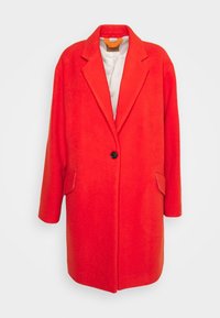 Cappotto rosso monopetto con rever a incasso, un bottone nero, tasche con pattina e fodera interna di colore chiaro.