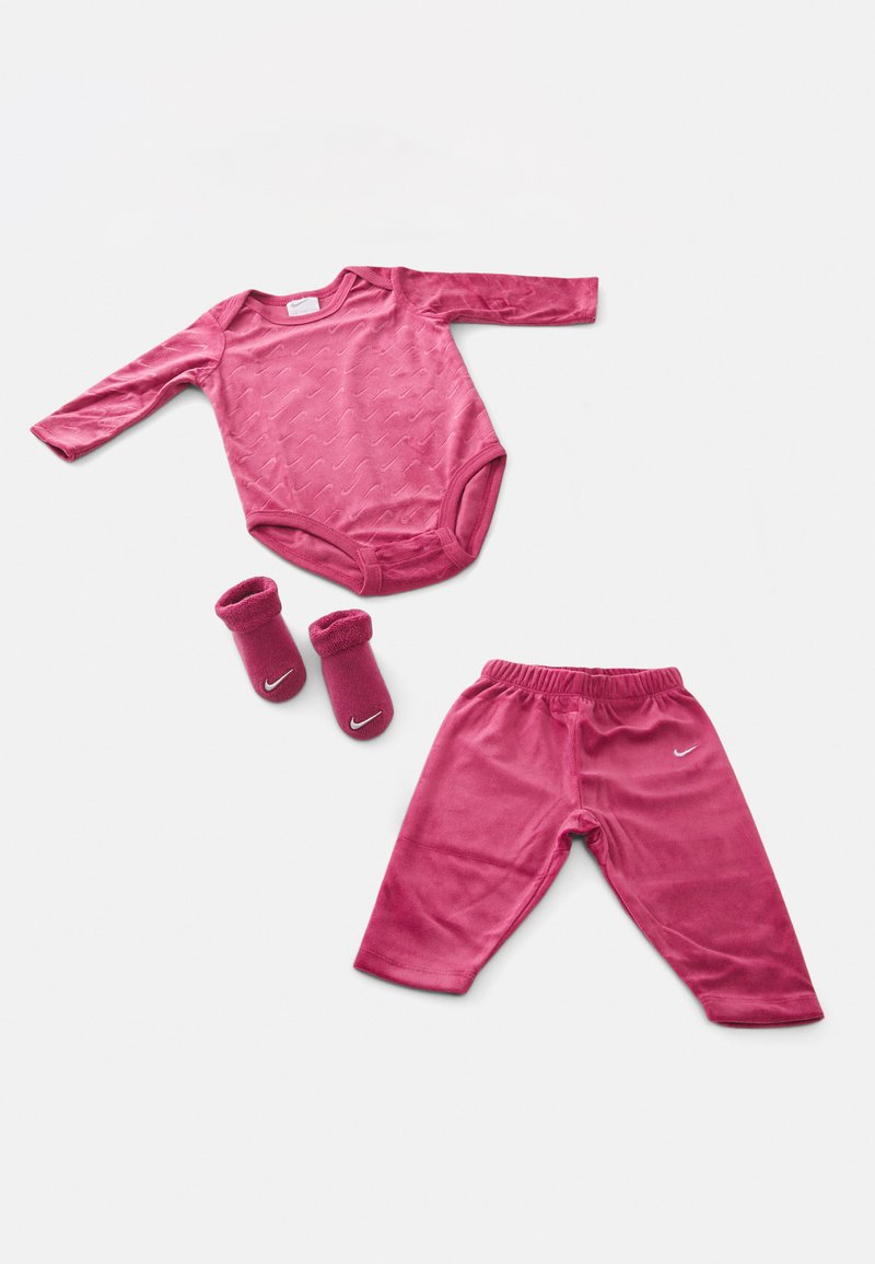 Roosa pika varrukaga bodysuit, millel on tekstuurne disain, sobivad roosad püksid ja sokid kontsaga, millel on Nike logo. Pehme kangas ja lõdva istuvusega.