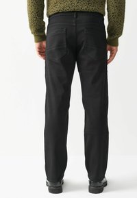 Čierne denimové džínsy so strihom typu straight fit, s dvoma zadnými vreckami, viditeľným šitím a s textúrovaným zeleným sveterom na páse.