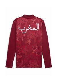 Langärmliges bordeauxfarbenes Polohemd mit gemustertem Rücken, das weißen arabischen Text und geometrische Designs in dunkleren Rottönen zeigt.