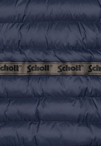 Mørkeblå polstret jakke med kviltet design. Indeholder en beige strop med sort "Schott" logo hen over midten. Glat, reflekterende tekstur.