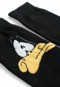 Calzini neri con design di personaggi dei cartoni animati in giallo e bianco, che mostrano una superficie liscia e un dettaglio di polsino a coste.