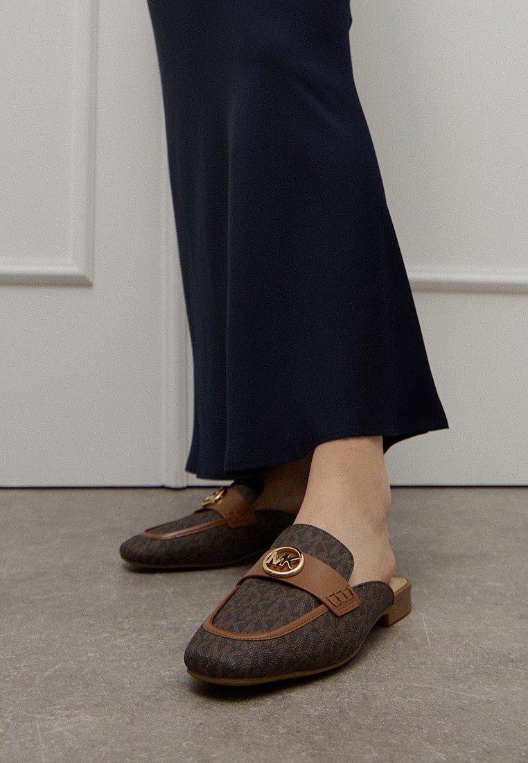 Donkerbruine loafers met een geometrisch patroon, leren accenten en een gouden logo gesp. Platte hak; ontworpen voor casual gebruik.