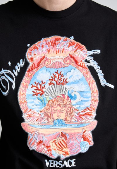 T-shirt en coton noir présentant un design graphique coloré avec des motifs marins, incluant des coraux, des coquillages et un visage central, avec un texte blanc au-dessus.