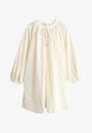 Blouse à manches longues de couleur crème avec texture à motif de feuilles, encolure arrondie et détail noué devant, manches légèrement froncées et poignets élastiques.