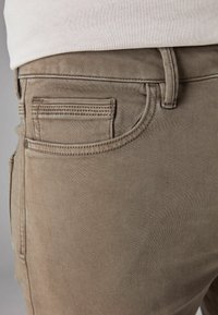 Beez denim püksid koos lähedaluku tagatasku ja õmbluse detailidega. Lame tekstuur ja klassikaline 5-tasku disain.
