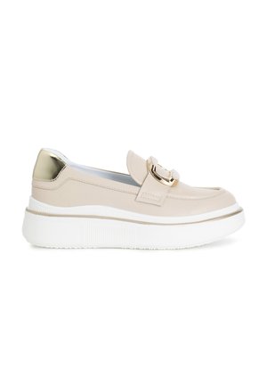 Scarpa slip-on in pelle beige con accentuazione dorata e fibbia decorativa, caratterizzata da una suola piatta bianca con dettagli testurizzati.