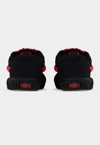 Baskets noires et rouges avec une semelle en caoutchouc texturée, un col rembourré et un logo signature rouge au talon. Tige en matériau lisse.