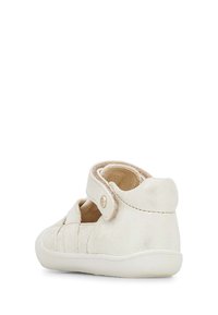 Białe skórzane buty dla niemowląt z wycięciami, rzepem i miękką podeszwą; posiadają subtelny połysk i detale w postaci stębnowania. Lekkie i elastyczne w designie.