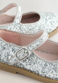 Scarpe Mary Jane argentate glitterate con punta rotonda, tomaia in tessuto, cinturino regolabile con fibbia e interno imbottito rosa.