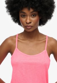 Roze tanktop met dunne bandjes, gemaakt van lichtgewicht stof. Soepele textuur met een ronde halslijn en een losse pasvorm.