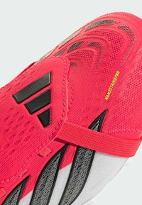 Κόκκινο αθλητικό παπούτσι με υφασμάτινο επάνω μέρος, μαύρες λεπτομέρειες, ιμάντα και σόλα με σχέδιο, με τη σήμανση "NANOSTRIKEPRO".