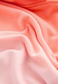 Tejido suave y elástico en tonos degradados de coral y rosa claro, con una textura lisa y un delicado detalle de canalé en toda la superficie.