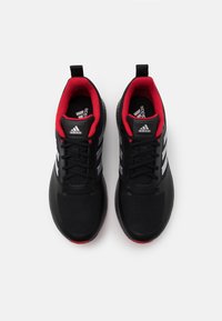 Ein Paar schwarze Adidas-Laufschuhe mit weißen Streifen und rotem Innenfutter, von oben auf einem weißen Hintergrund betrachtet.