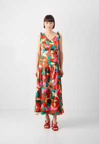 Robe maxi au motif floral éclatant avec des rouges, des roses, des verts et des jaunes. Design sans manches avec un ourlet volanté et des accents à nouer.
