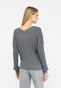 Maglione grigio a coste con scollatura a V, maniche lunghe e tessuto testurizzato. Presenta un bottone sul colletto e una vestibilità morbida.